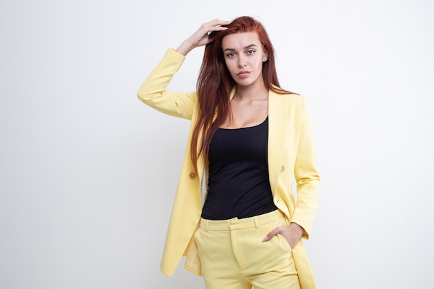 Bella mujer con pelo rojo posando en traje amarillo