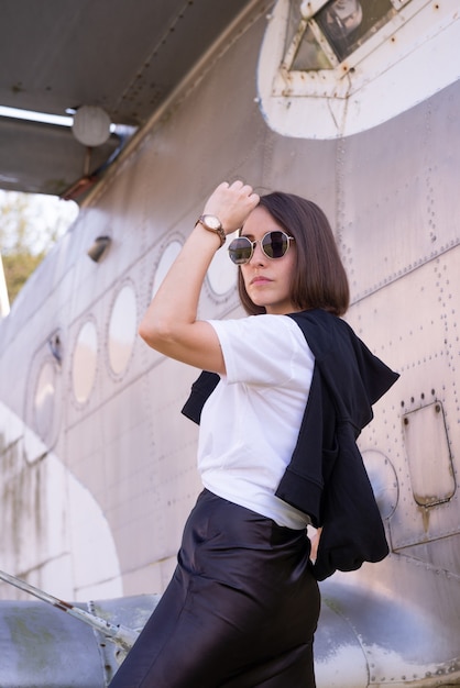 Bella mujer posando con un avión retro