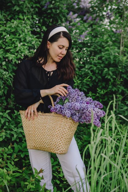 Bella mujer posando con flores lilas se acerca el verano