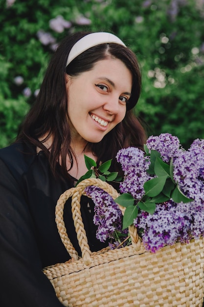 Bella mujer posando con flores lilas se acerca el verano