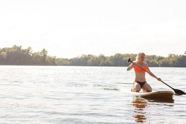 Una bella mujer practicando paddle en un hermoso día soleado