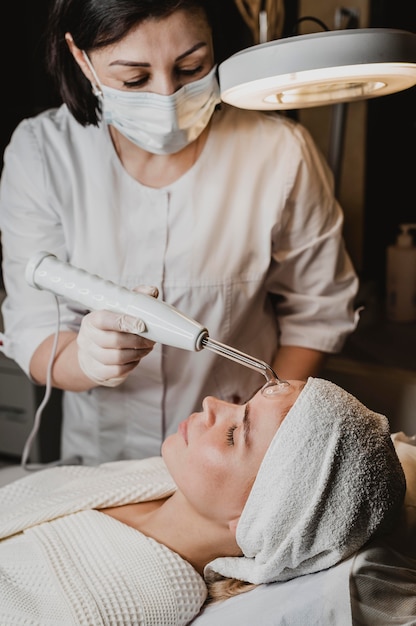 Foto bella mujer recibiendo un tratamiento facial en el centro de bienestar