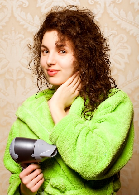 Bella mujer secándose el cabello con secador de pelo