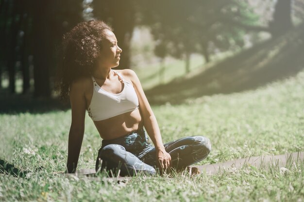 Bella mujer sentada en el césped y relajarse después del ejercicio