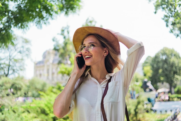 Bella mujer con sombrero de fieltro hablando por teléfono