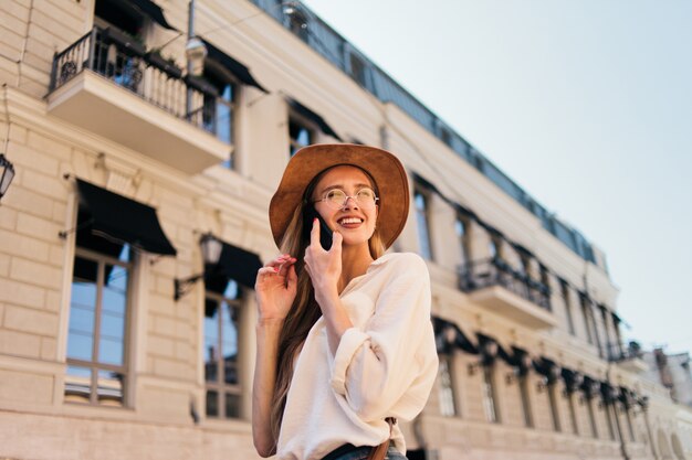 Bella mujer con sombrero de fieltro hablando por teléfono