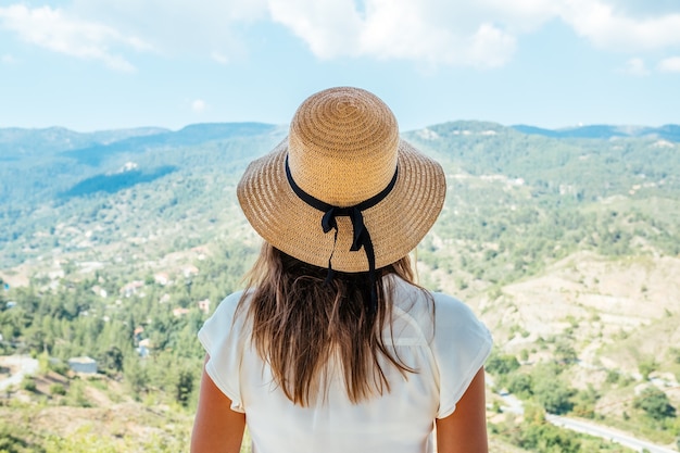 Bella mujer con sombrero de paja mirando hacia la vista del valle