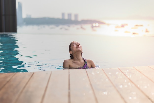 Bella mujer sonriendo en una piscina bajo la luz del verano