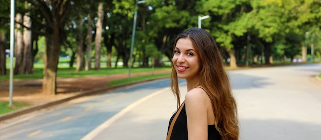 Bella mujer sonriente caminando en el Parque Ibirapuera, Sao Paulo. Vista panorámica de banner.