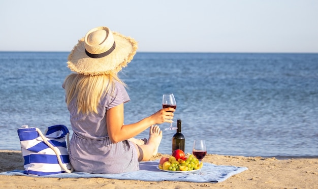 Bella mujer sonriente con una copa de vino en la playa. Vino tinto de frutas.