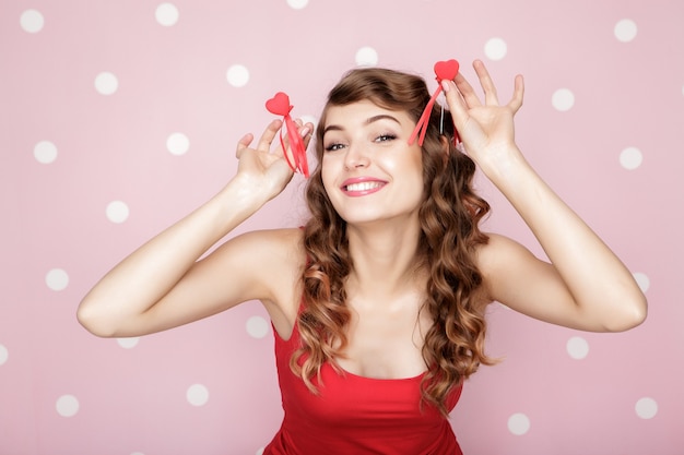 Bella mujer sonriente con corazones rojos para el día de San Valentín