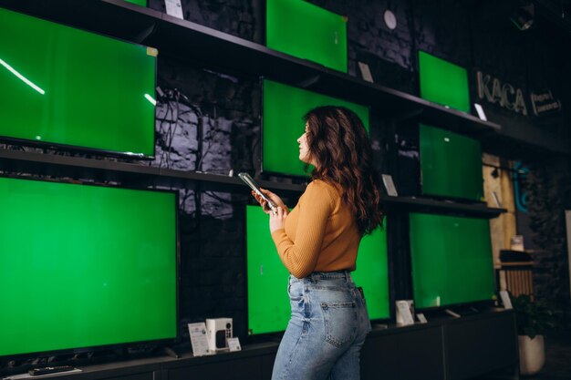 Una bella mujer en una tienda de electrónica elige un televisor.