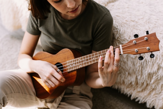 Una bella mujer toca una guitarra pequeña