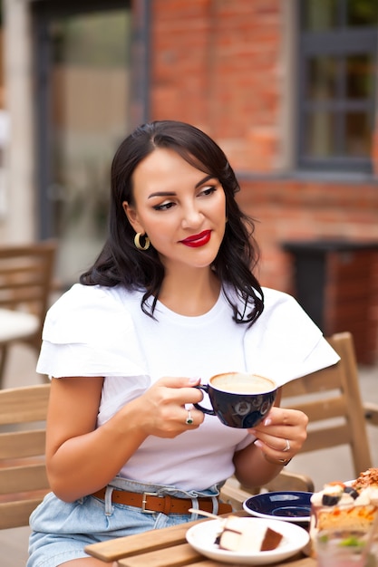 Bella mujer tomando café en una cafetería y comiendo croissant