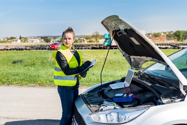 Bella mujer tomando notas mientras diagnostica el coche