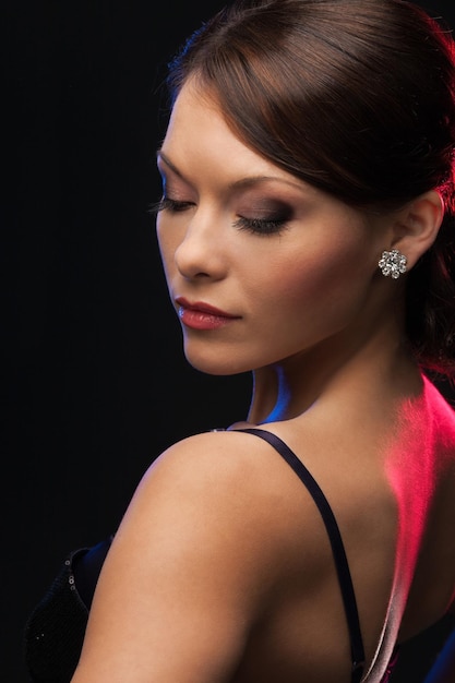 Bella mujer en traje de noche con aretes de diamantes