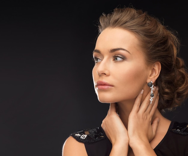 Bella mujer en traje de noche con aretes de diamantes