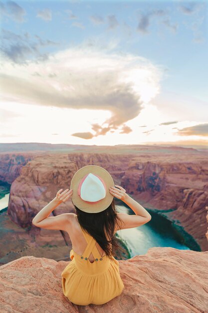 Bella mujer con vestido amarillo en el borde del acantilado en Horseshoe Band Canyon en Paje Arizona hermosa naturaleza en Estados Unidos