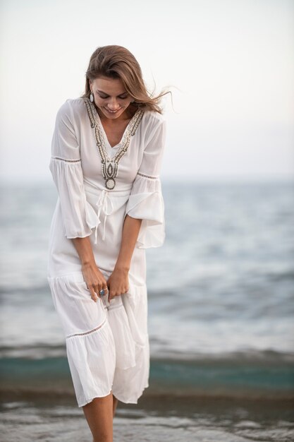 Bella mujer en vestido blanco junto al mar