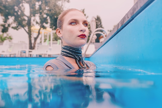 bella mujer con vestido gris saltando en la piscina