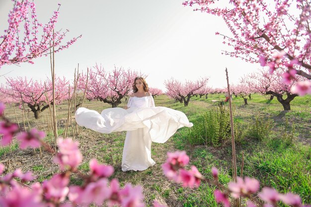 Una bella mujer con un vestido largo blanco como una novia en un parque público