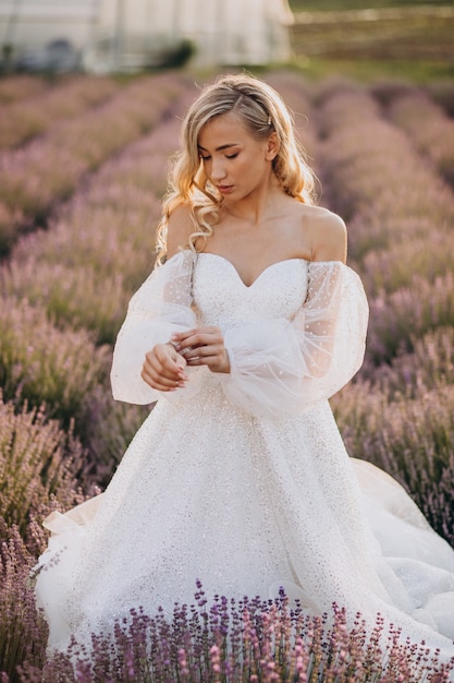 Bella mujer en vestido de novia en campo lavanda