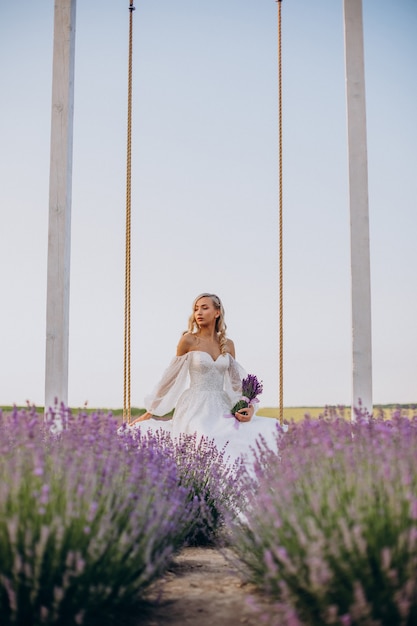 Bella mujer en vestido de novia en campo lavanda