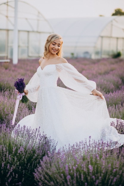 Bella mujer en vestido de novia en campo lavanda