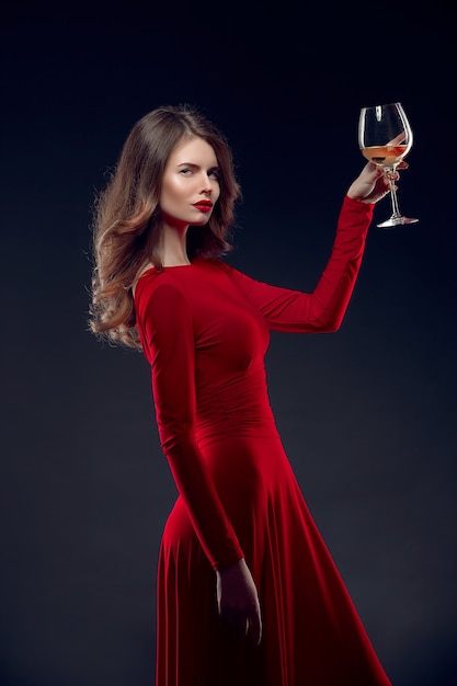 Bella mujer con un vestido rojo con una copa de vino