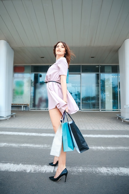 Bella mujer con un vestido rosa con bolsas de la compra.