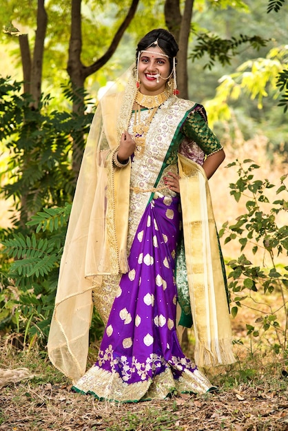 Bella novia india en un sari tradicional posando al aire libre en el parque