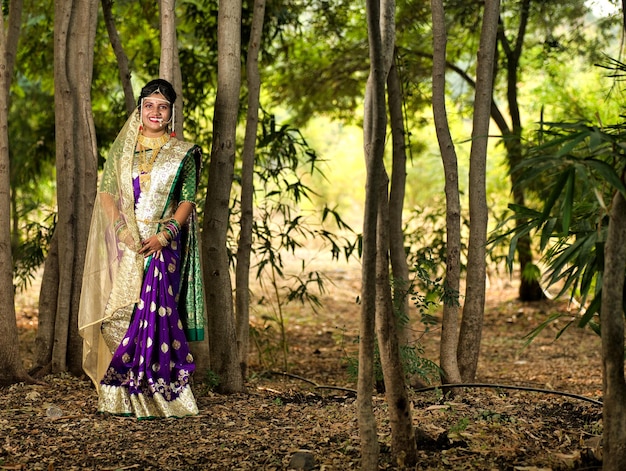 Bella novia india en un sari tradicional posando al aire libre en el parque