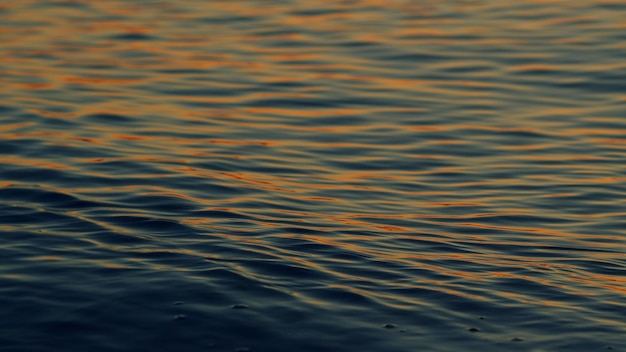 Bella puesta de sol sobre las ondas del océano en la superficie del agua del mar o lago al atardecer en cámara lenta