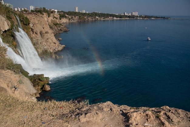 Bella vista de la cascada con arco iris que desemboca en el mar