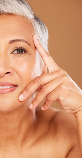 Foto belleza de anciana y retrato de media cara en estudio aislado en un fondo marrón cosméticos de maquillaje de lujo y modelo anciana jubilada pensando en el cuidado de la piel facial, salud y bienestar de la piel