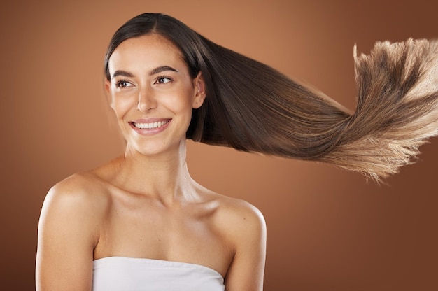 Belleza del cabello y cuidado de la piel con una mujer modelo en estudio sobre un fondo marrón para un tratamiento natural o de queratina Cuidado del cabello y salón de belleza con una atractiva mujer joven posando para promocionar un producto