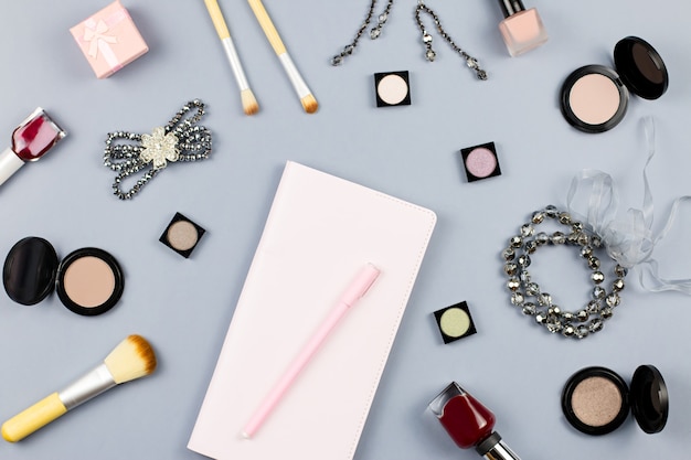Belleza, concepto de blogger de moda. Accesorios de moda, cuaderno y cosméticos en superficie plana gris.