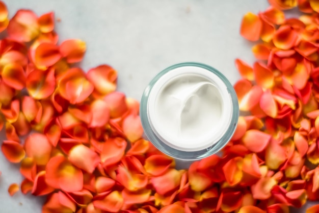 Belleza crema hidratante facial y pétalos de flores en mármol producto cosmético de lujo