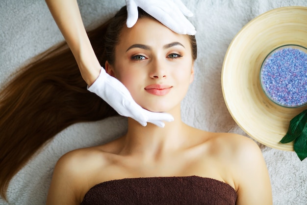 Belleza y cuidado, hermosa joven relajante en spa, masaje facial