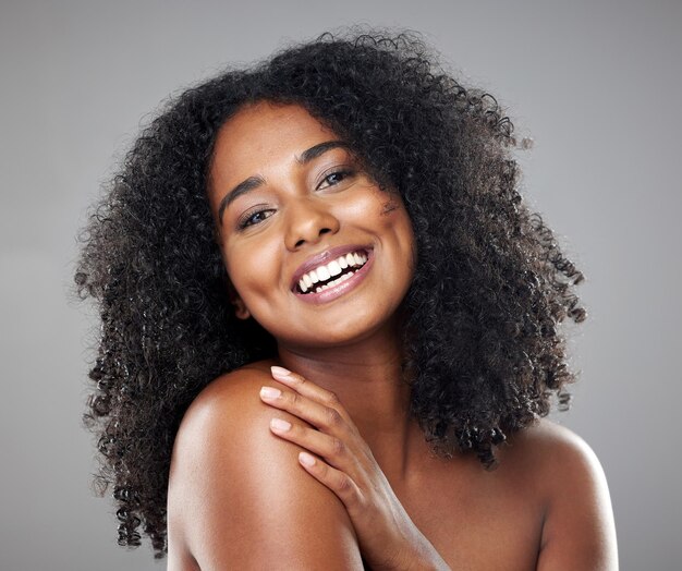 Belleza facial y cuidado de la piel con una mujer negra modelo en estudio sobre un fondo gris con una sonrisa feliz Cosméticos de retrato y bienestar con una atractiva joven posando para promocionar un producto