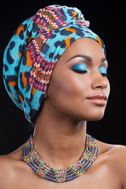 Belleza fascinante. Hermosa mujer africana con un pañuelo en la cabeza y un collar manteniendo los ojos cerrados