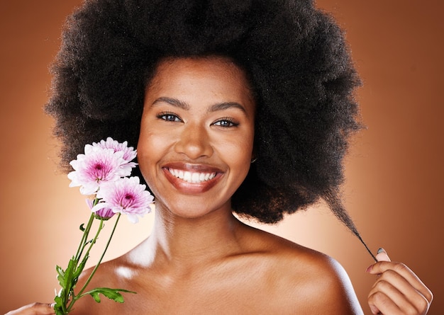 Belleza de flores y cuidado del cabello de un retrato de mujer negra con brillo de piel y bienestar Modelo de mujer con afro feliz por el lujo natural y la belleza cosmética con una sonrisa y flores para tratamiento facial