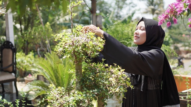 La belleza del hijab corta las hojas en el jardín.