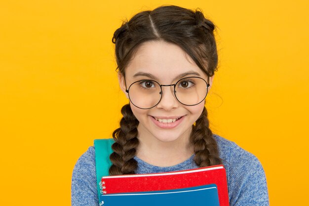 Belleza inteligente. Niña feliz en fondo amarillo coletas. Peluquería. Mirada de belleza de niño pequeño. Tienda de óptica. Ópticas. Cuidado de ojos. Lentes correctivos. Manteniendo tu belleza y tu vista frescas.