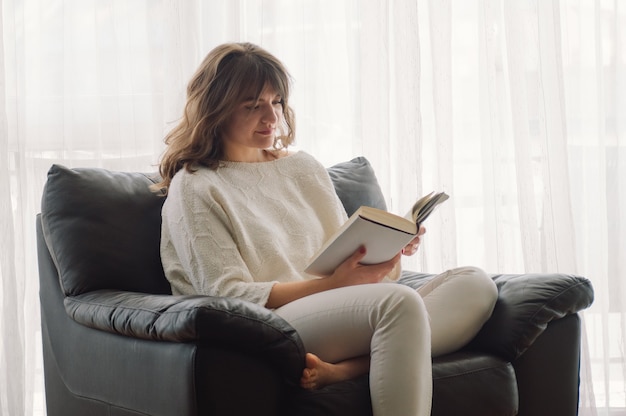 Belleza joven está leyendo un libro en casa