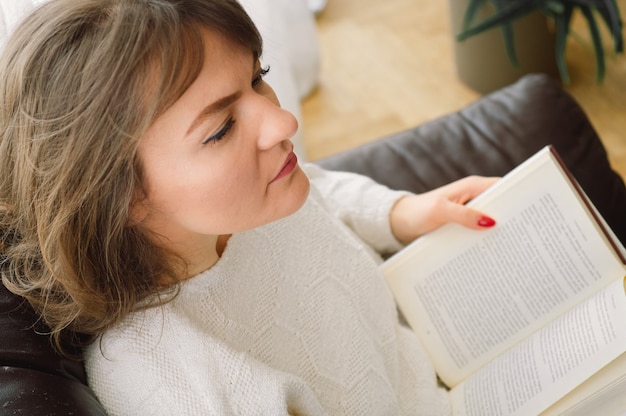 Belleza joven está leyendo un libro en casa