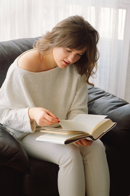 Belleza joven está leyendo un libro en casa