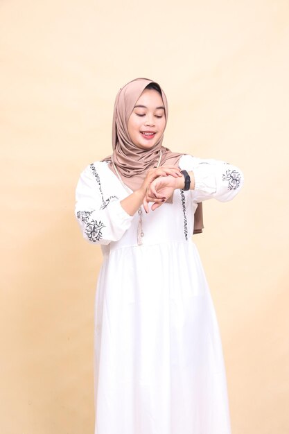 la belleza de una joven musulmana asiática con un hijab sonriendo mirando un reloj con una oración