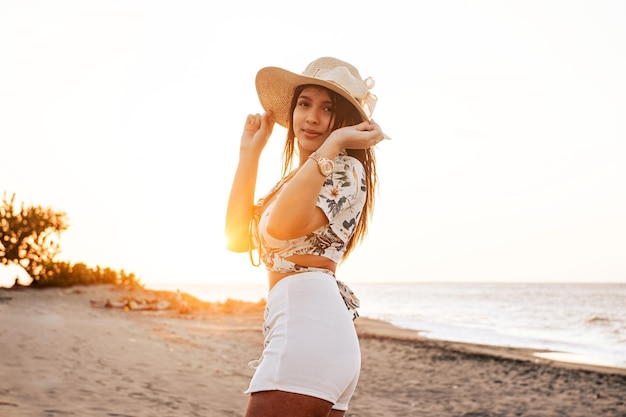 Belleza joven sonriendo con un sombrero en la playa