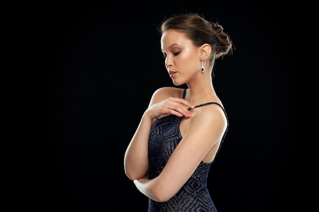 belleza, joyas, accesorios de boda, gente y concepto de lujo - hermosa mujer asiática con pendiente de diamantes sobre fondo negro